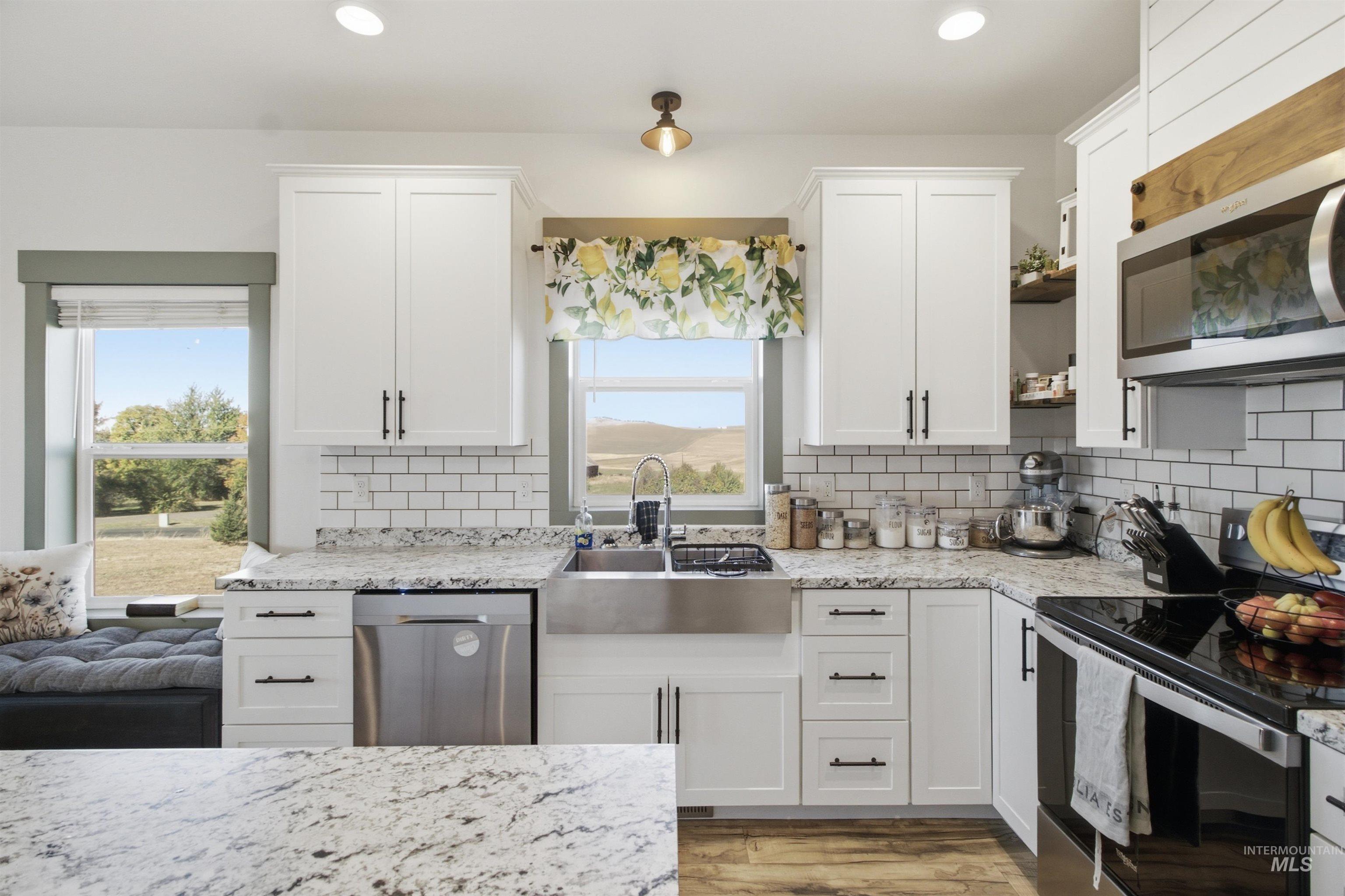 1032 Duffield Flat Road Potlatch, ID 83855 - Photo 12 of 50 White shaker cabinetry, stainless steel appliances, granite countertops, subway tile backsplash, and wood-finish flooring