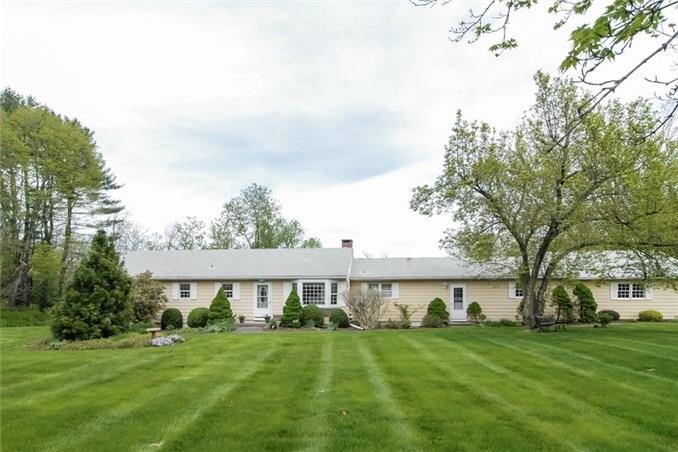 a view of a big house with a big yard and large trees
