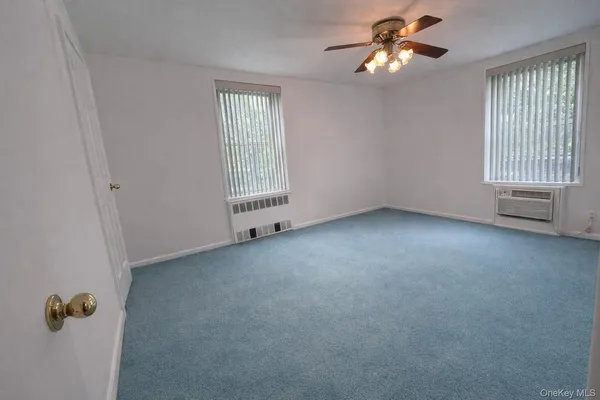 an empty room with a window and a fan