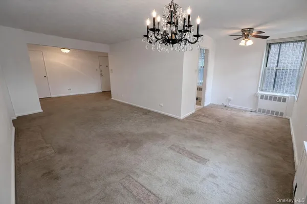 a view of a room with a chandelier fan and a window