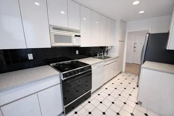 a kitchen with granite countertop a stove a sink and a refrigerator