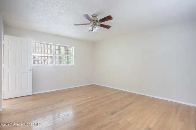 an empty room with a ceiling fan and windows
