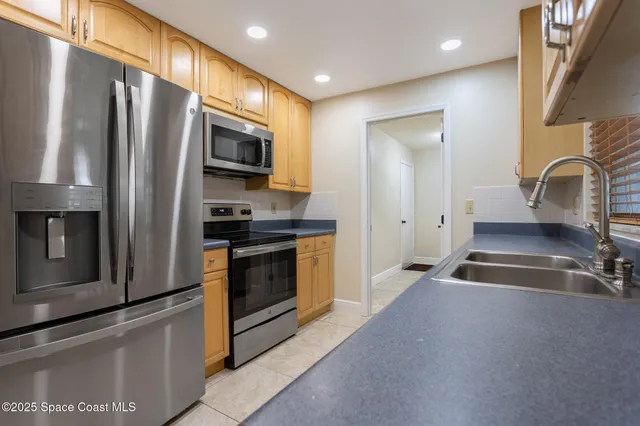 a kitchen with stainless steel appliances granite countertop a refrigerator a stove and a sink with wooden floor