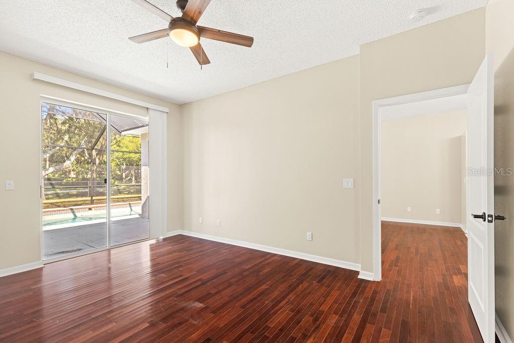 10641 Firebrick Court Trinity, FL 34655 - Photo 20 of 47 an empty room with wooden floor chandelier fan and windows