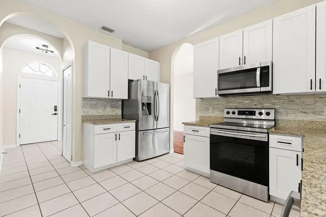 a kitchen with stainless steel appliances granite countertop a stove a refrigerator and a microwave