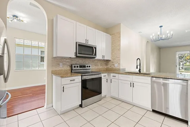 a kitchen with white cabinets appliances and a window