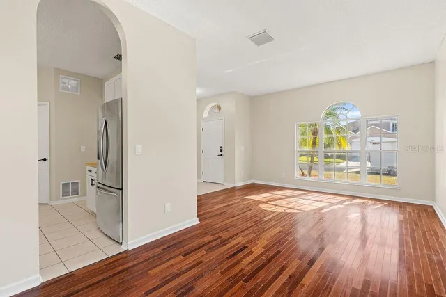 a view of empty room with wooden floor and fan