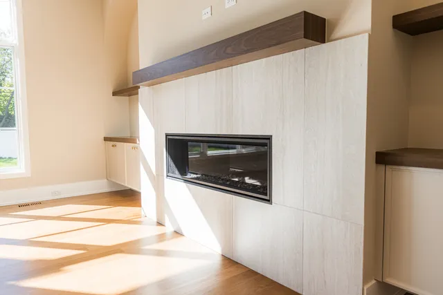 a view of an empty room with wooden floor and a fireplace