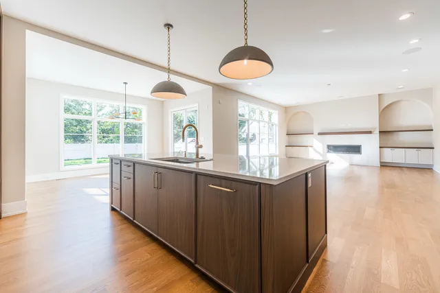 a kitchen with kitchen island granite countertop a stove a sink a center island and wooden floor