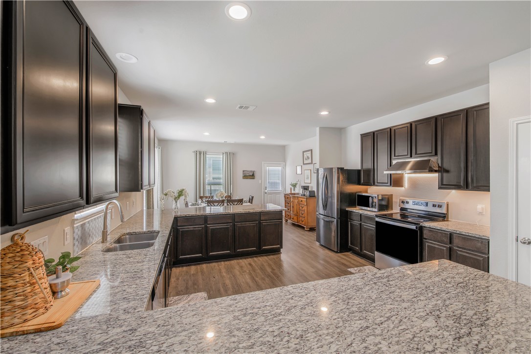4703 Coyotillo Way Bryan, TX 77807 - Photo 8 of 24 a large kitchen with kitchen island a large counter top stainless steel appliances and cabinets