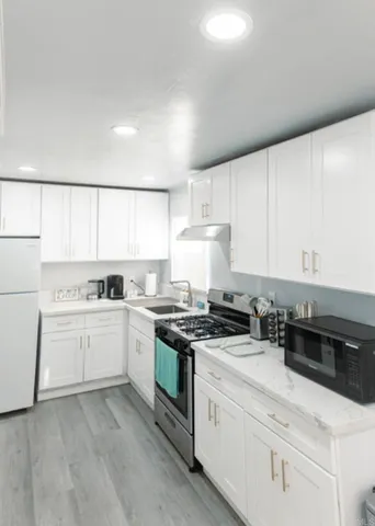 a kitchen with granite countertop white cabinets and white appliances