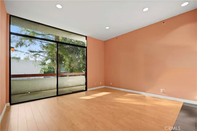 a view of an empty room with wooden floor and windows