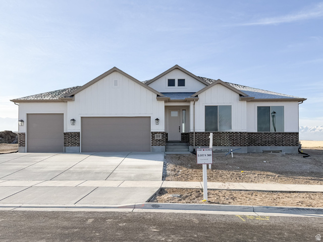 Modern farmhouse featuring an attached garage, driveway, brick siding, board and batten siding, and a shingled roof