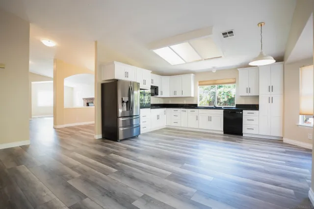 a kitchen with stainless steel appliances kitchen island granite countertop a refrigerator and a wooden floors