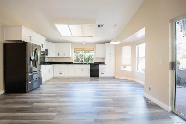 a view of a kitchen with a sink refrigerator and wooden floor