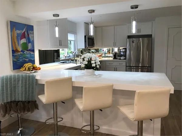 a kitchen with stainless steel appliances kitchen island granite countertop a refrigerator a stove a sink dishwasher and white cabinets with wooden floor