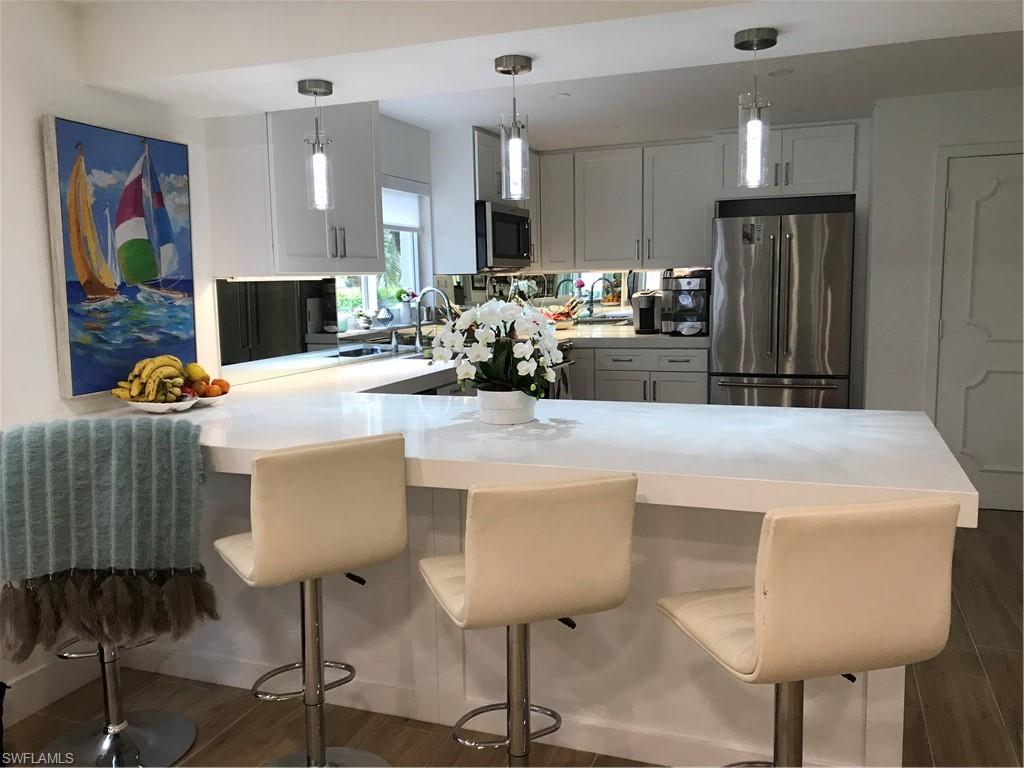 302 2nd Street South, Unit 302 Naples, FL 34102 - Photo 4 of 14 a kitchen with stainless steel appliances kitchen island granite countertop a refrigerator a stove a sink dishwasher and white cabinets with wooden floor