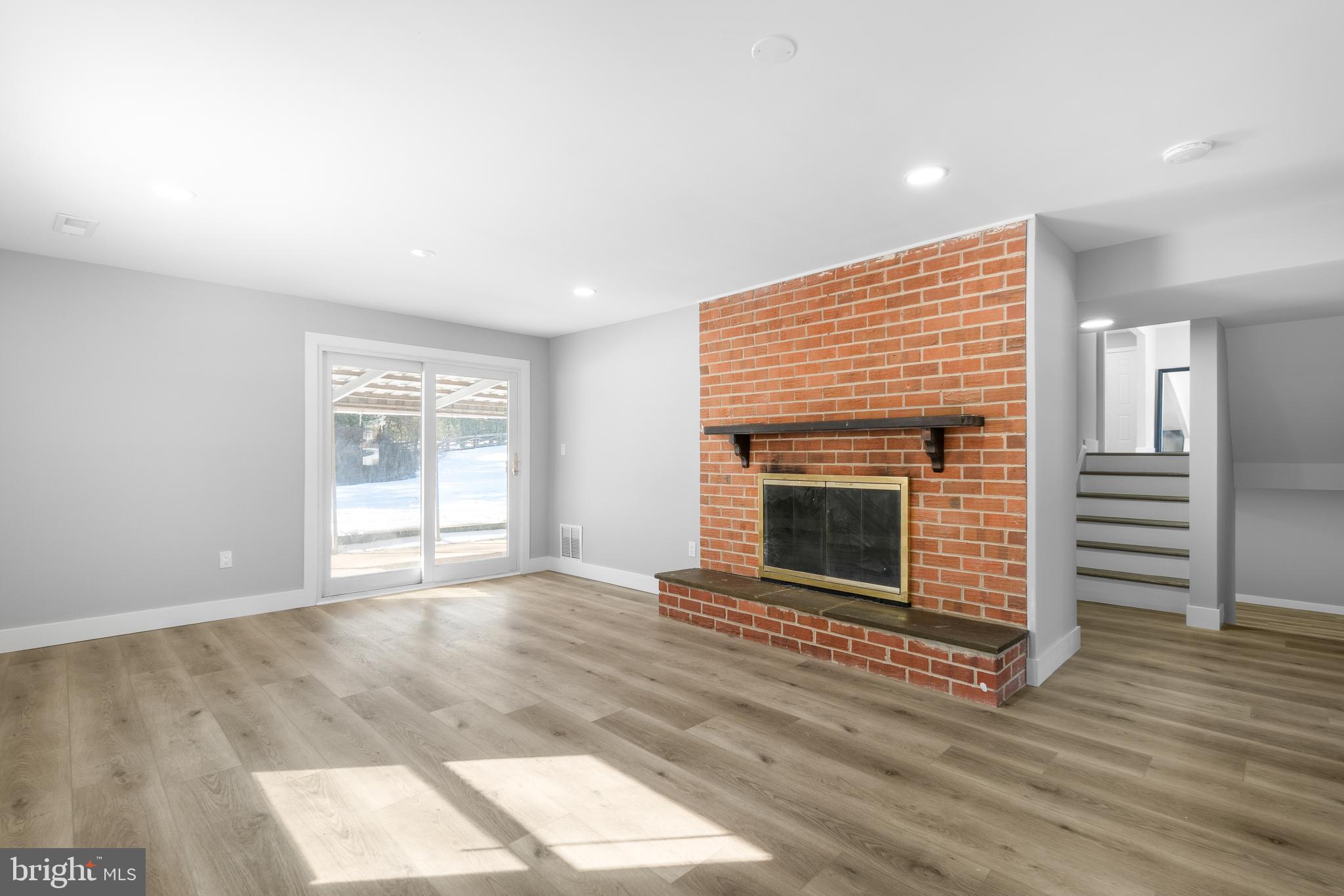 19104 Bloomfield Road Olney, MD 20832 - Photo 24 of 37 an empty room with wooden floor fireplace and windows