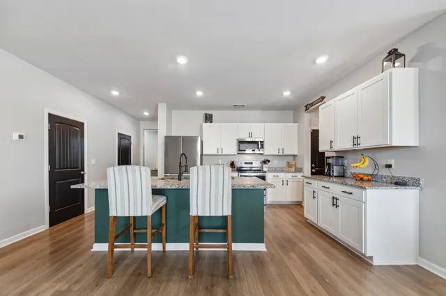 a kitchen with stainless steel appliances granite countertop a stove a sink and a white cabinets