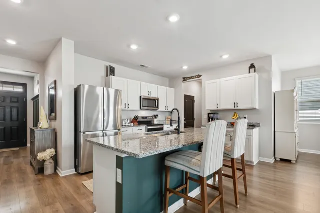 a kitchen with stainless steel appliances kitchen island granite countertop a table chairs sink and cabinets