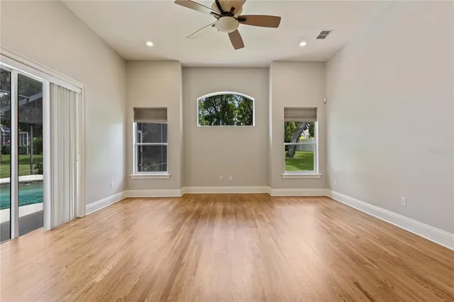 an empty room with windows and fan