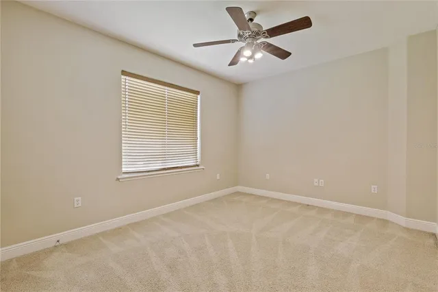 an empty room with chandelier fan and windows