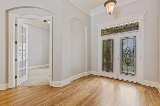 an empty room with wooden floor mirror and windows