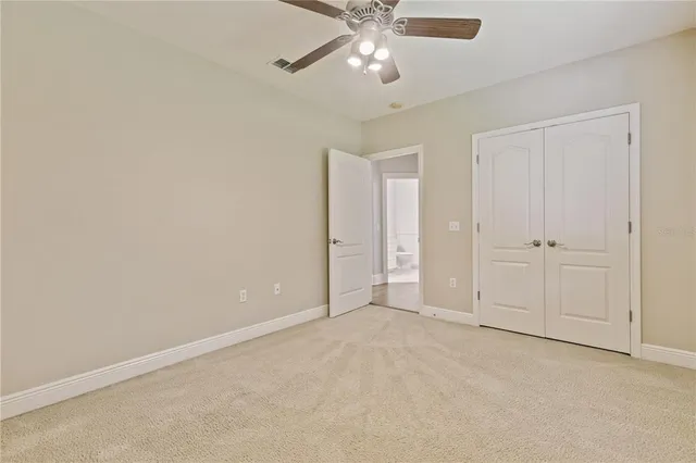 an empty room with a chandelier fan and windows