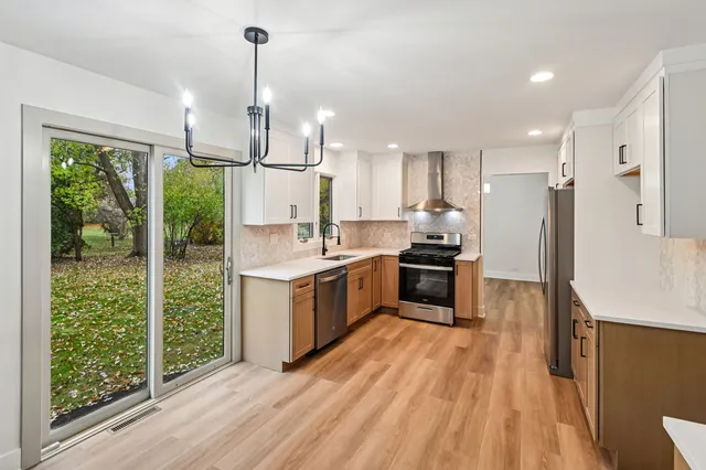 a kitchen with kitchen island a counter top space a sink stainless steel appliances and cabinets