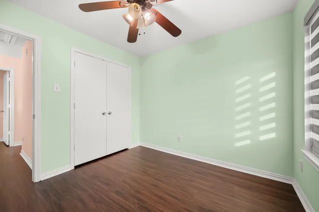 an empty room with wooden floor chandelier fan and windows