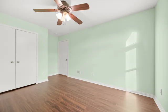 an empty room with wooden floor closet and fan
