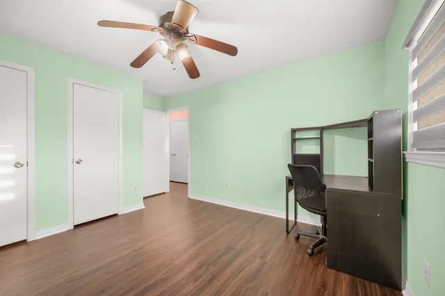 an empty room with wooden floor fan and windows