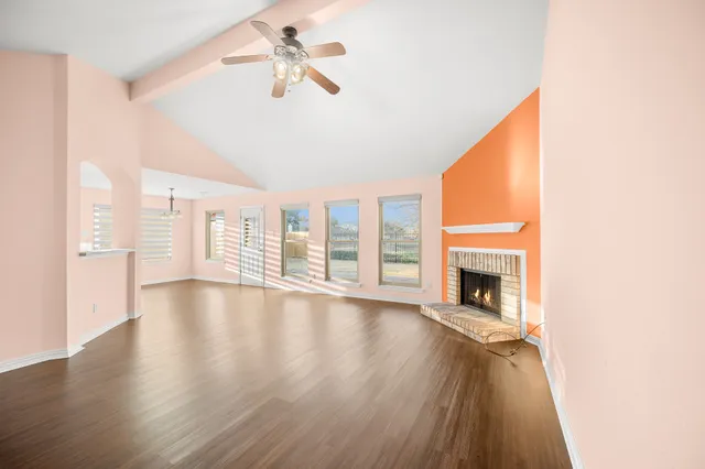 a view of an empty room with window and wooden floor