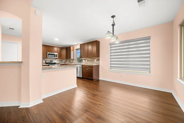 a kitchen with stainless steel appliances granite countertop a refrigerator a stove top oven a sink dishwasher and white cabinets with wooden floor