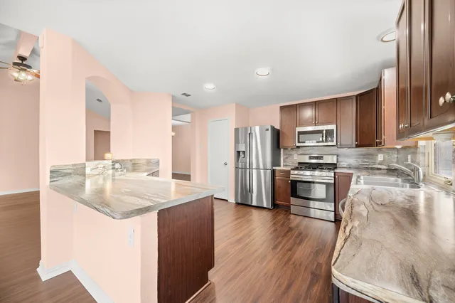 a kitchen with stainless steel appliances granite countertop a sink refrigerator and microwave