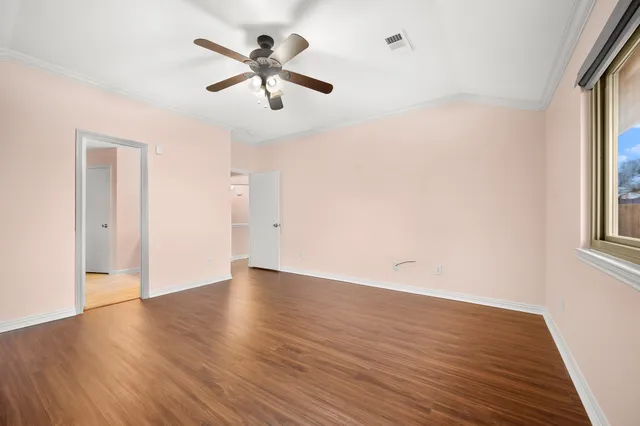 an empty room with wooden floor and windows