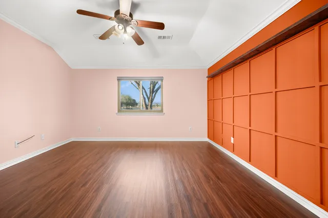 an empty room with wooden floor chandelier fan and windows