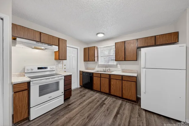 a kitchen with granite countertop a refrigerator stove top oven and sink