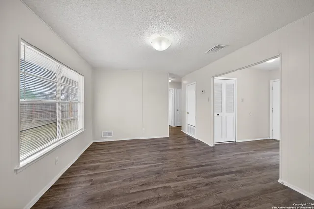 a view of an empty room with wooden floor and a window