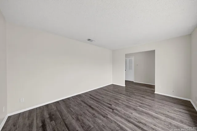 a view of an empty room with wooden floor