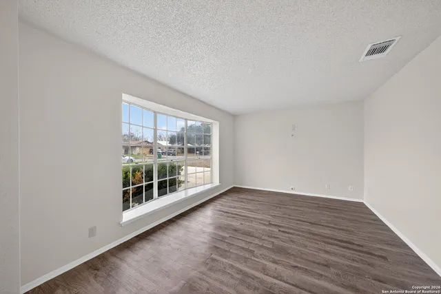 an empty room with wooden floor and windows