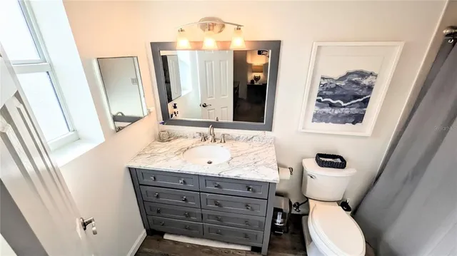 a bathroom with a granite countertop sink toilet and mirror