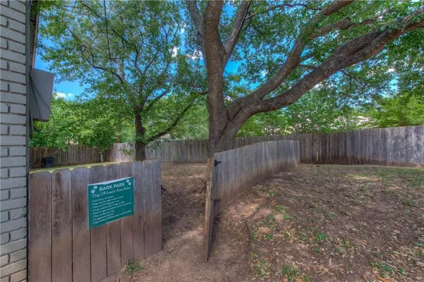 a view of a backyard with large trees and wooden fence