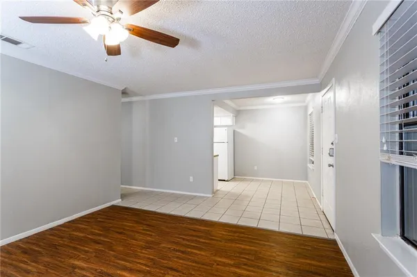 a view of a room with wooden floor a ceiling fan and windows