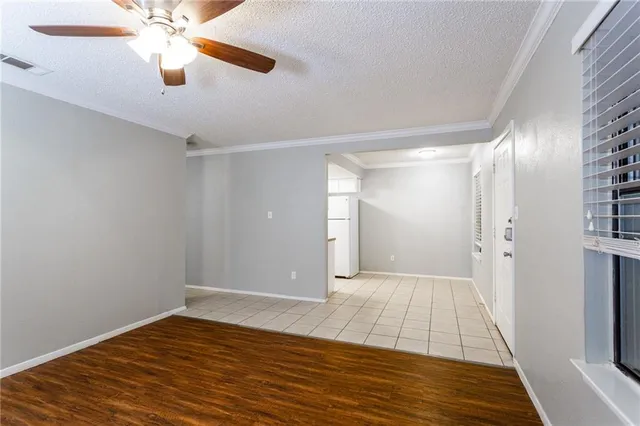 a view of a room with wooden floor a ceiling fan and windows