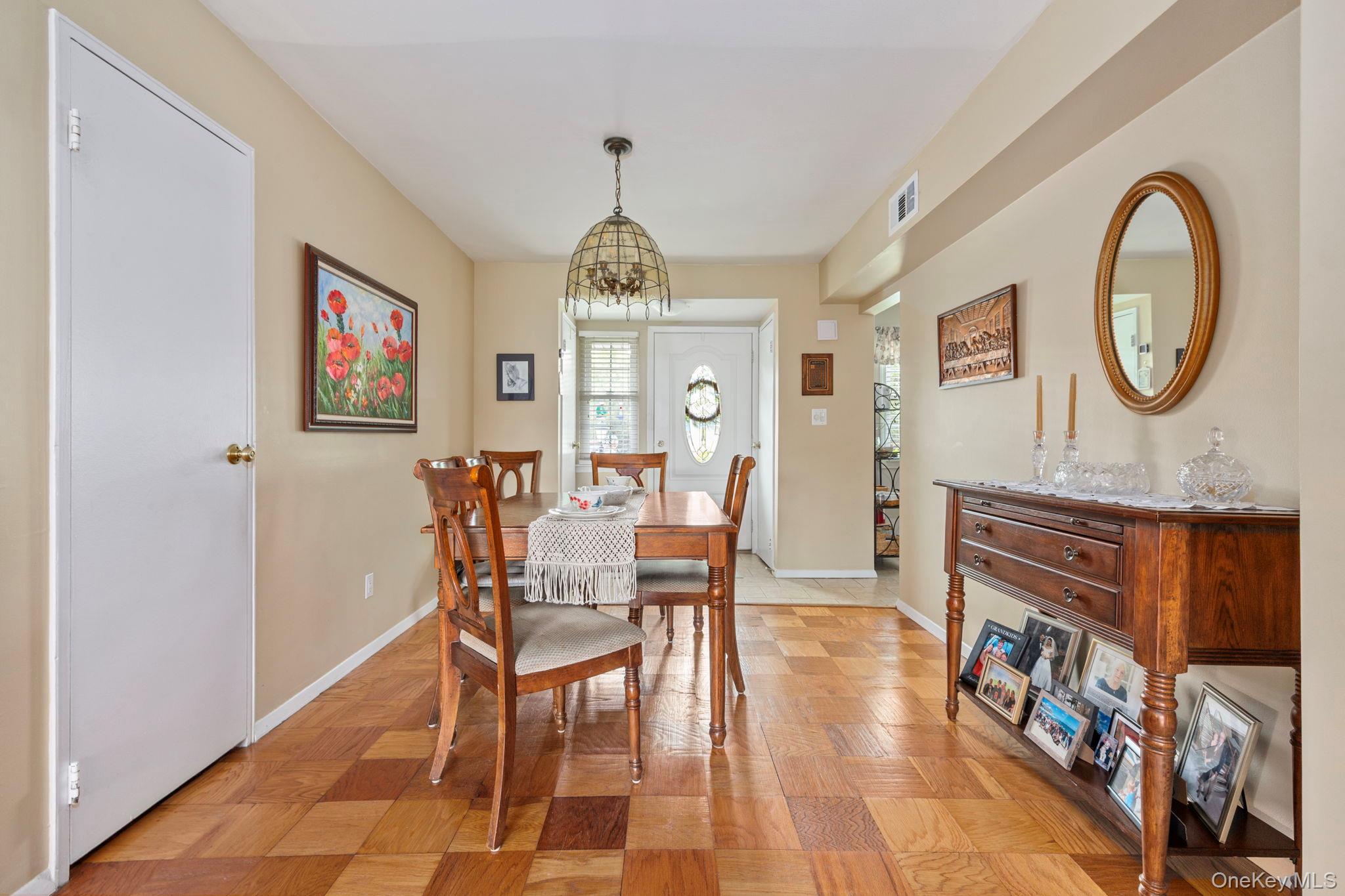 248 Mariners Way Copiague, NY 11726 - Photo 3 of 18 a dining room with wooden floor a painting on the wall and a clock