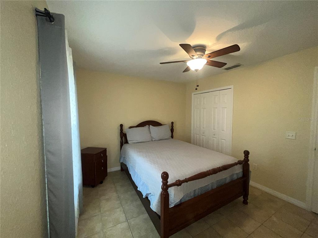 13615 Southeast 44th Terrace Summerfield, FL 34491 - Photo 16 of 26 a bed sitting in a bedroom next to a window and a ceiling fan