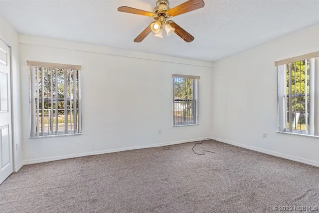 an empty room with windows and fan