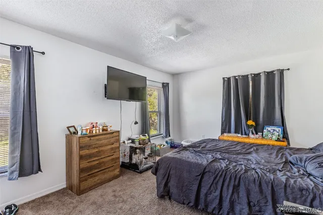a bedroom with a bed and a flat tv screen on wall