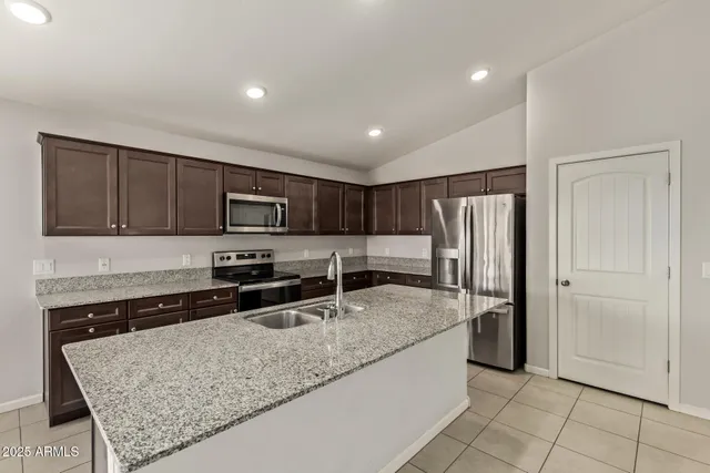 a kitchen with stainless steel appliances granite countertop a refrigerator a sink a stove a microwave and island